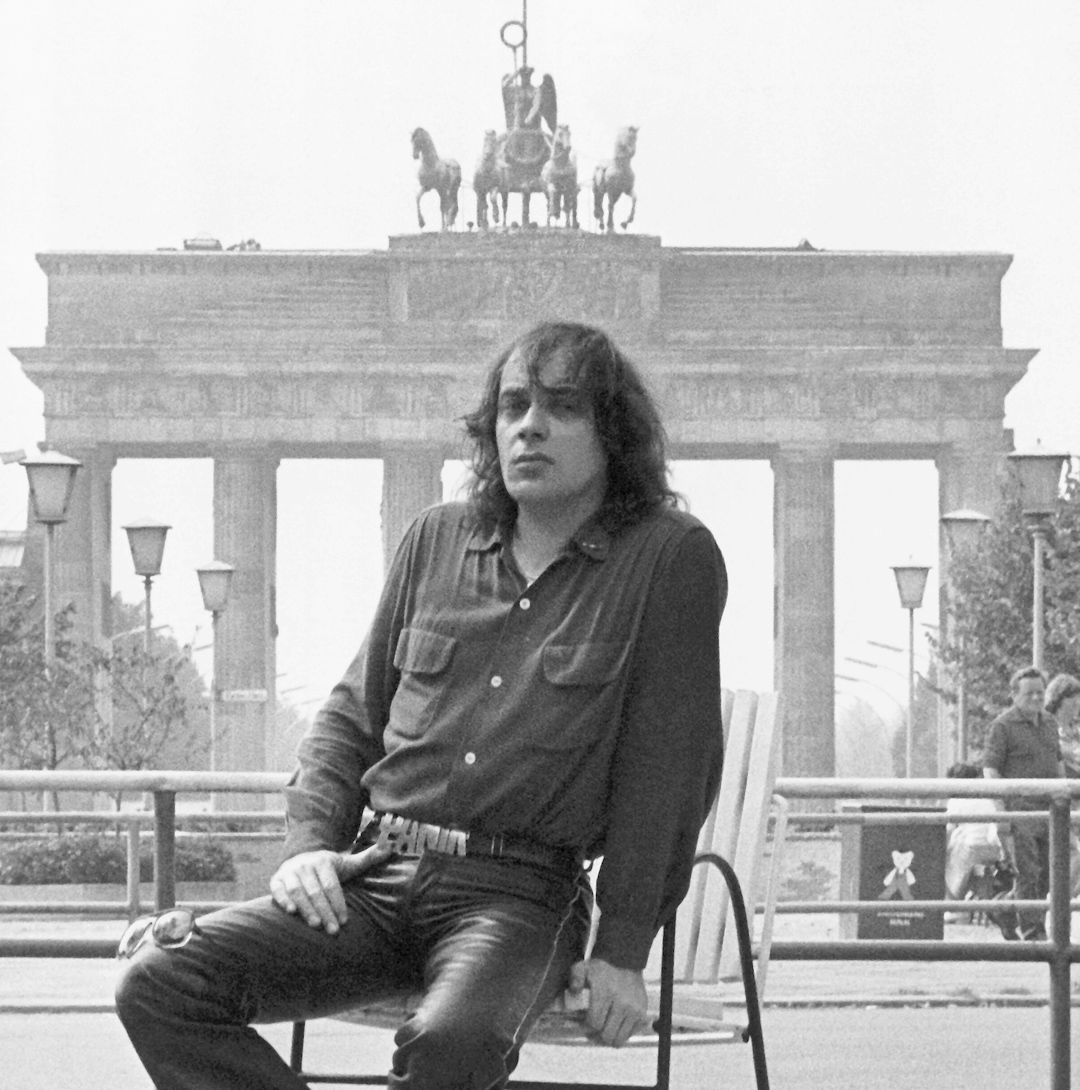 Udo Lindenberg sitzt vor dem Brandenburger Tor 1983 (schwarz-weiß)